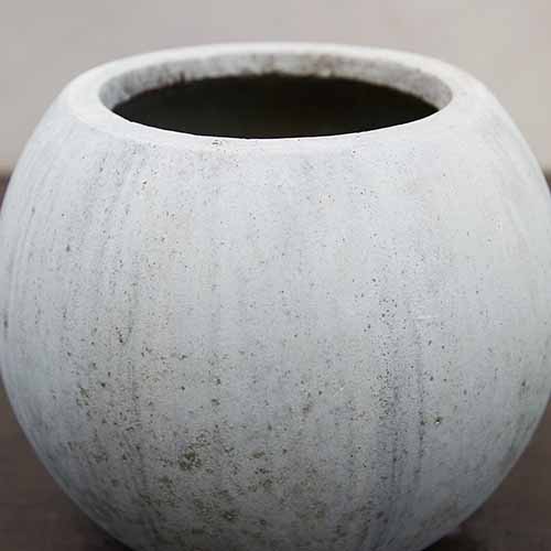 A close up square image of an unglazed round planter.