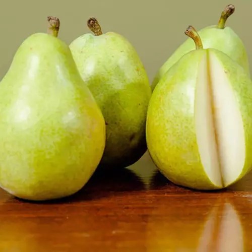 A close up of whole and sliced &lsquo;Hood&rsquo; pears set on a wooden surface.