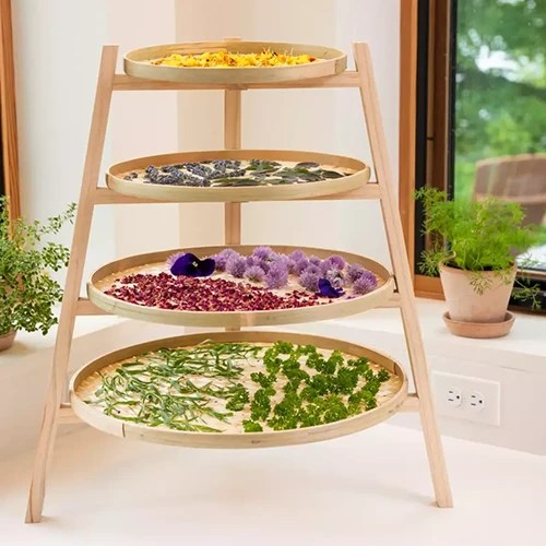 A close up of a bamboo herb drying rack set on a kitchen counter.