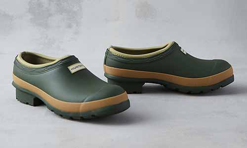 A close up of two Hunter women&rsquo;s garden clog in vintage green set on a gray surface.