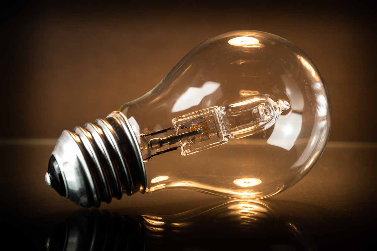 A close up horizontal image of a halogen bulb set on a dark surface.