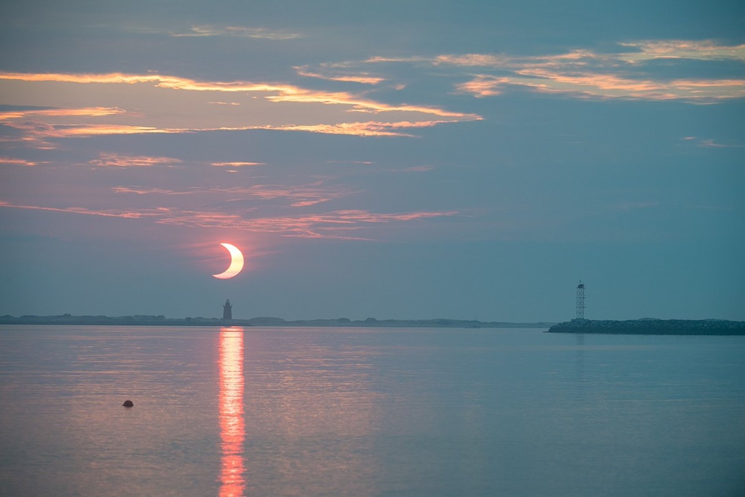 A partial solar eclipse as seen behind the Delaware Breakwater Lighthouse on June 10, 2021.