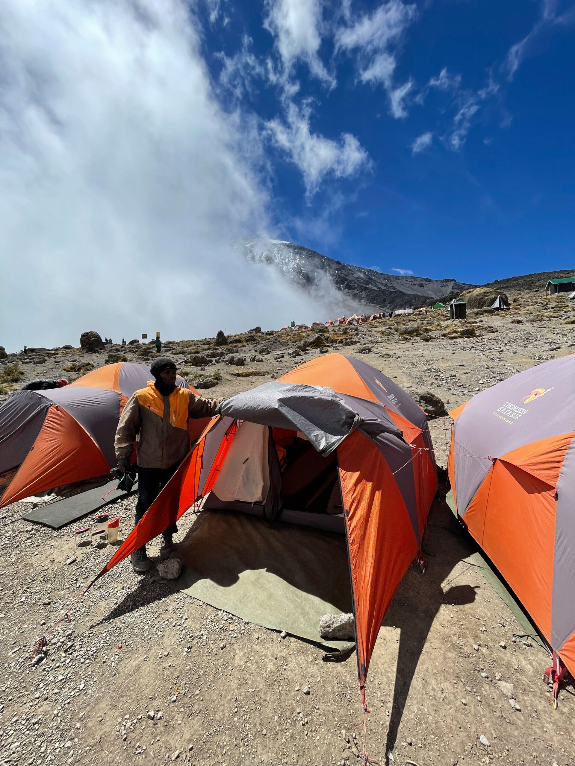 A Kilimanjaro trek team member invites us to enter our tent, our home for the evening, at Karanga Camp.