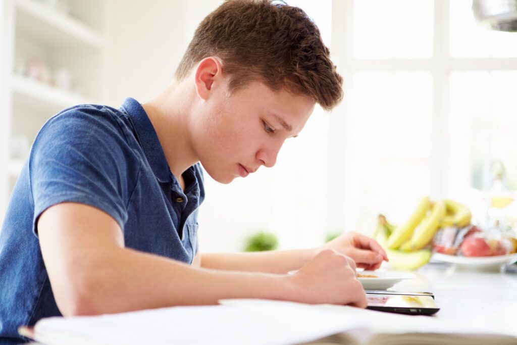 Teenage Boy Studying Using Digital Tablet At Home GradePower Learning
