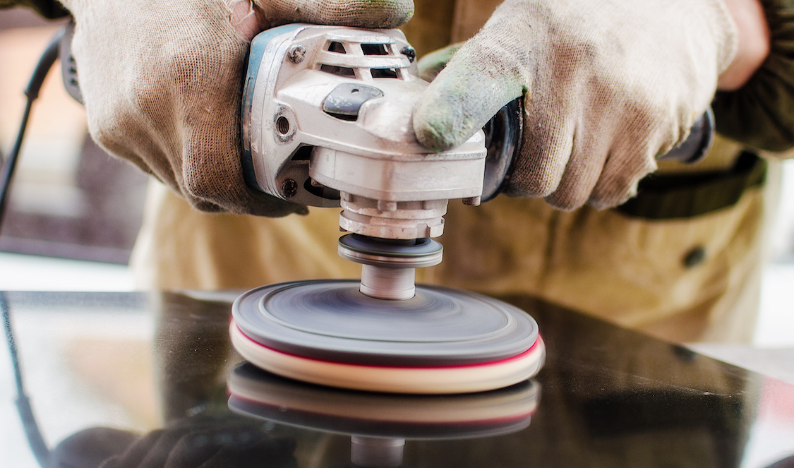 Worker polishes a stone with a grinder Granite Liquidators