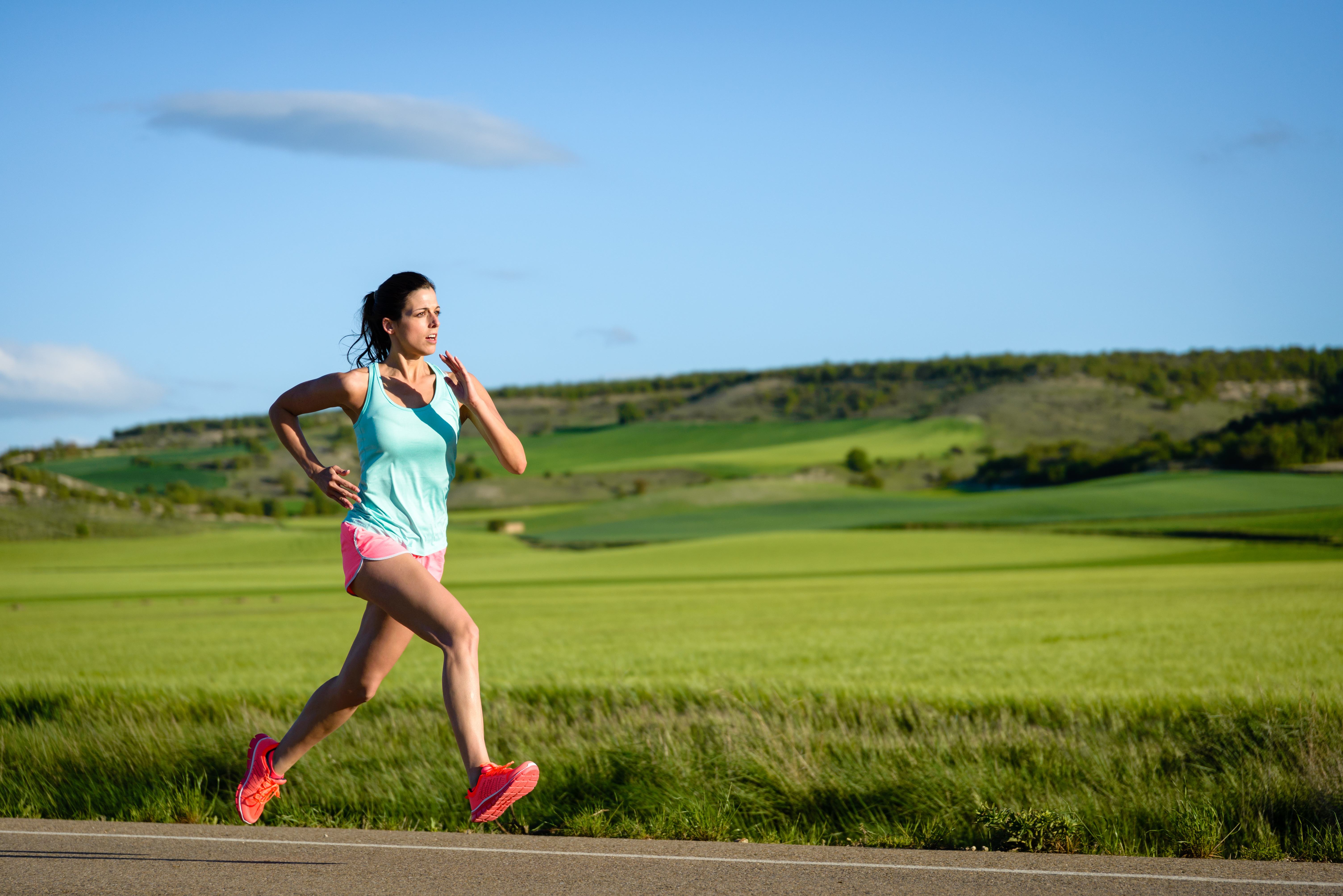 Sporty woman running fast on country side road. Female athlete training