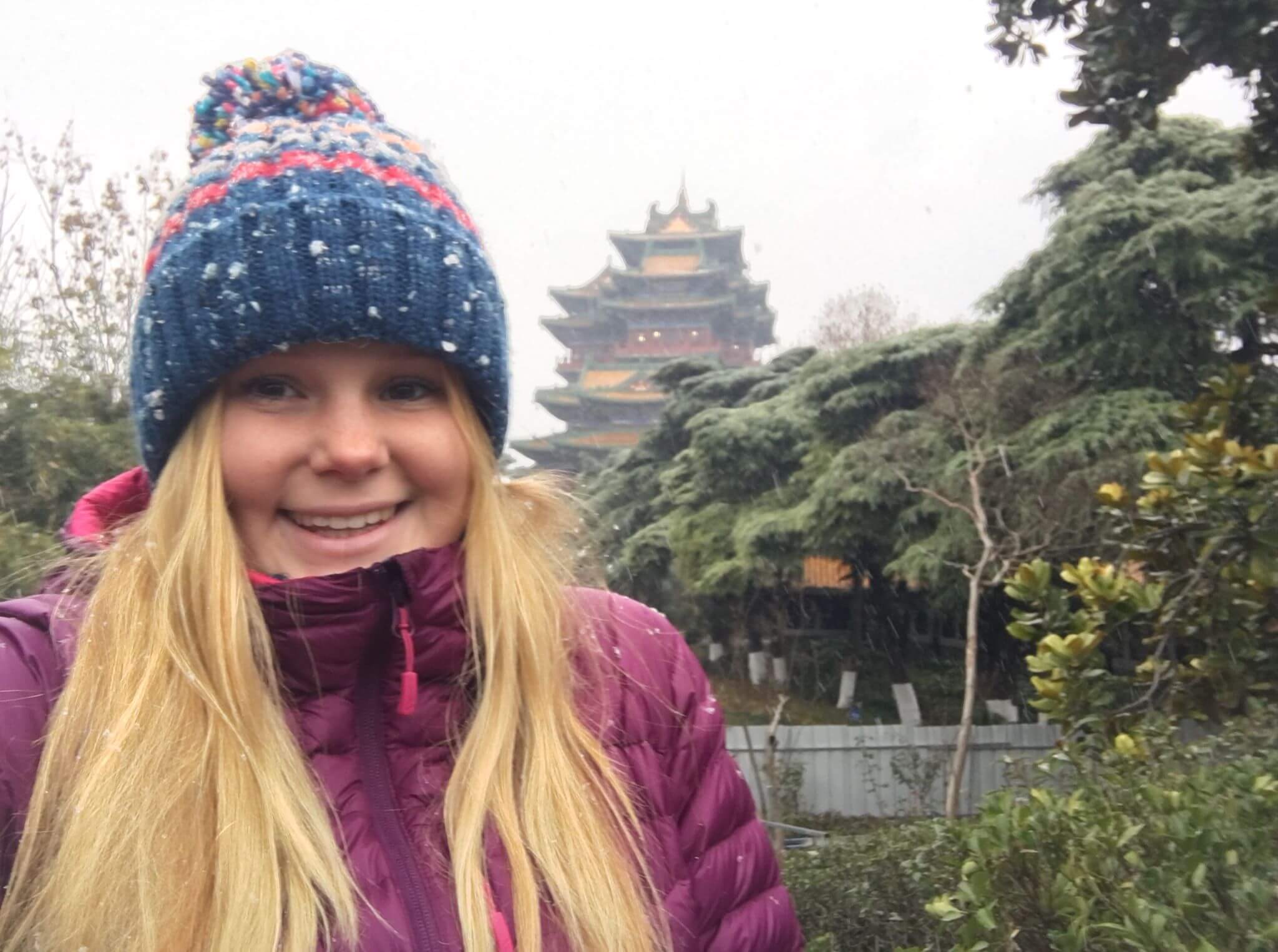 Woman in wooly hat smiling next to temple