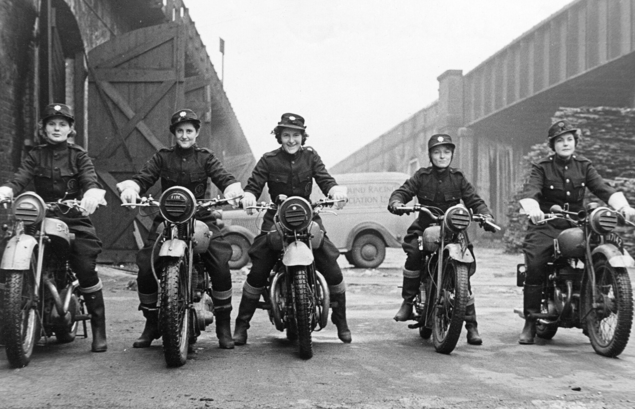 A black and white photograph of five women on motorcycles.