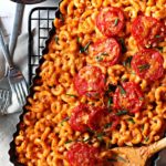 A casserole dish filled with Mexican Macaroni and Cheese topped with sliced tomatoes