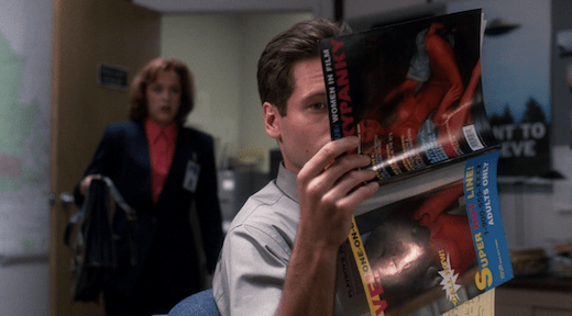 Mulder holds up a porn magazine vertically, presumably to look at the centerfold.