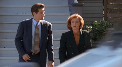 Mulder and Scully walk away from Lauren's house, both looking irritated.