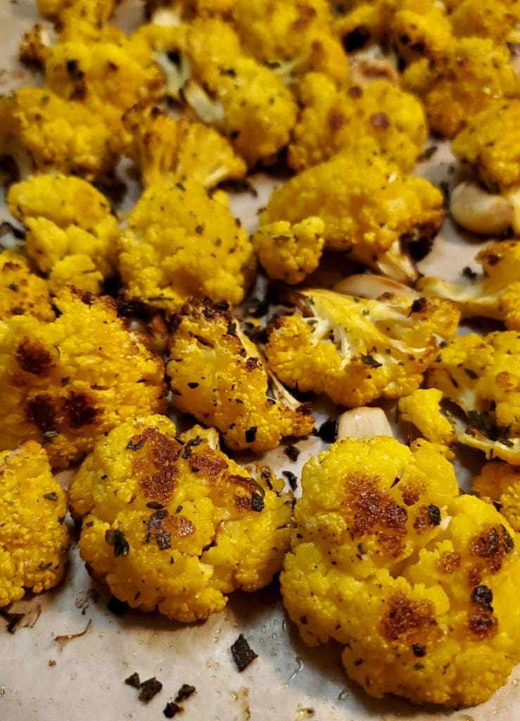 Roasted Cheddar florets on a baking sheet. The edges of the florets are brown from caramelization.