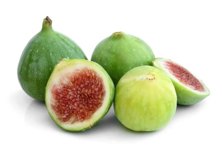 Quattro fichi verdi siedono uno accanto all'altro in un leggero guazzabuglio, alcuni di loro sono più di colore verde, mentre il fico più maturo è più verde giallastro. Uno è stato tagliato a metà per mostrare la sua carne ambrata.