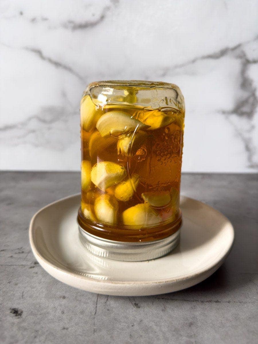 A full pint mason jar is sitting upside down on a small plate to fully coat the contents inside.