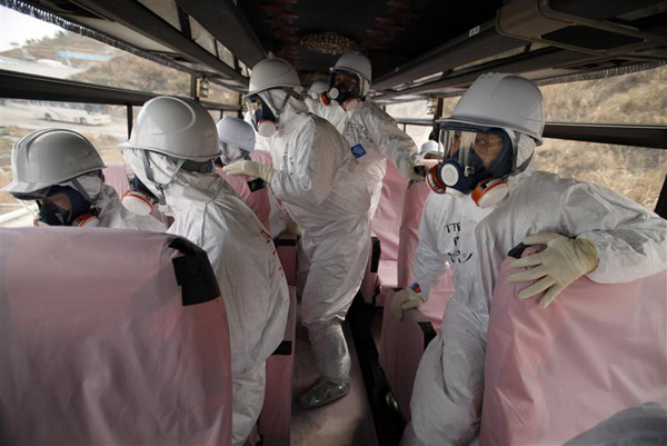 Officials from the Tokyo Electric Power Co. and members of media look at TEPCO's tsunami-crippled Fukushima Daiichi nuclear power plant from bus windows in Fukushima prefecture
