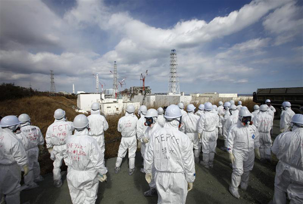Members of the media wearing protective suits and masks are escorted by TEPCO employees at Tokyo Electric Power Co.'s tsunami-crippled Fukushima Daiichi nuclear power plant