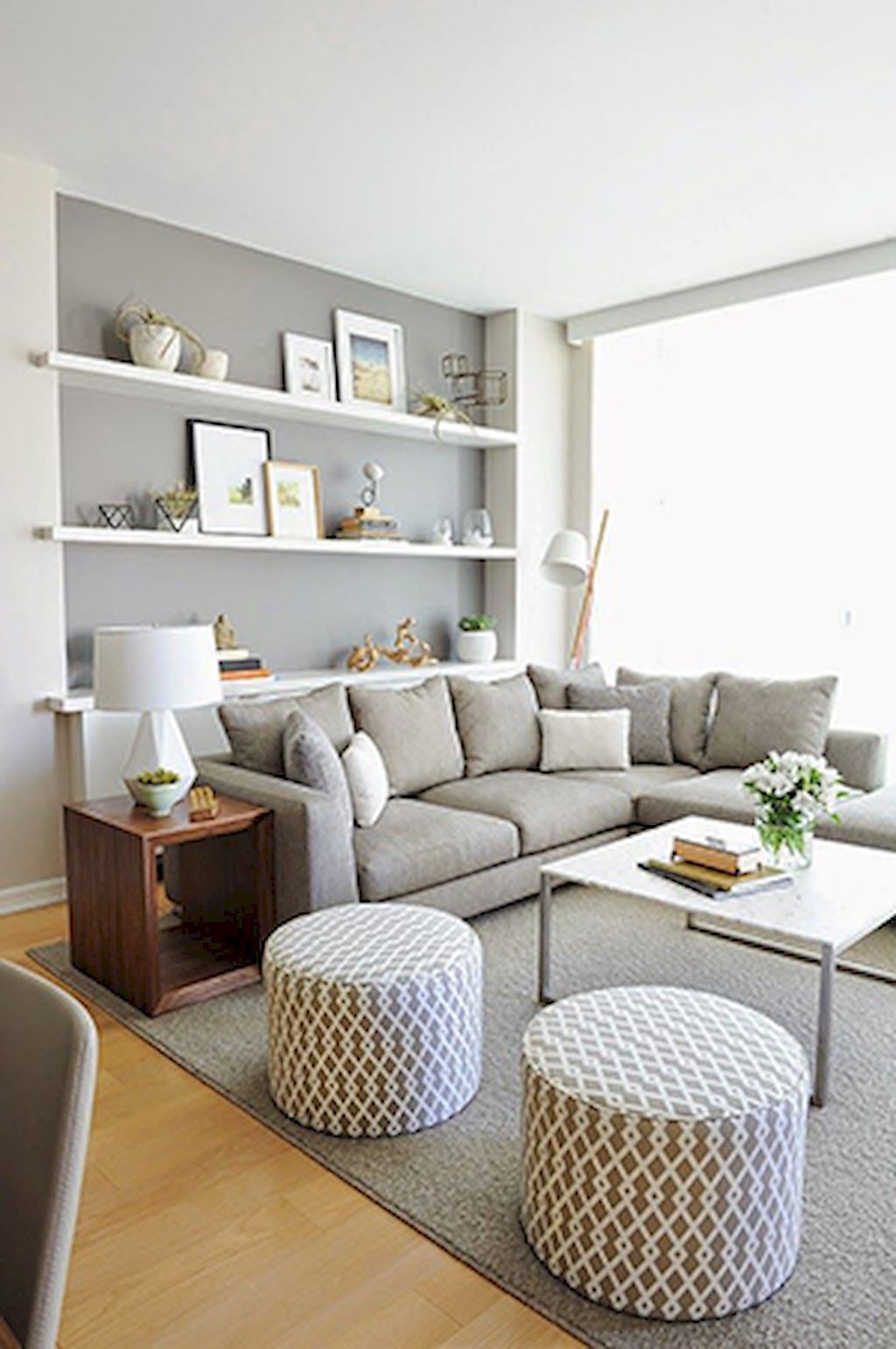 Photo of a white living room with grey L shape sofa with a bookcase built into the wall behind the sofa