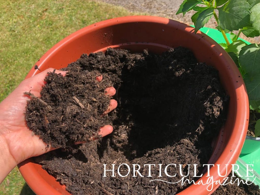 hand scooping compost from a planter