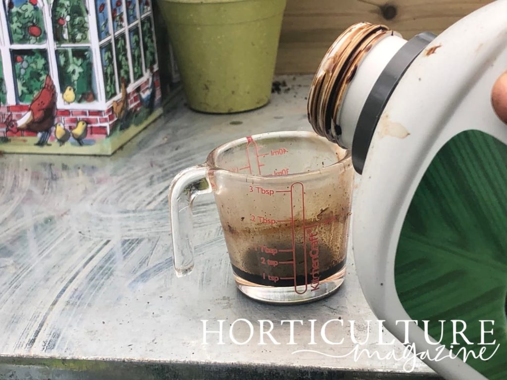 bottle pouring fertiliser into a small measuring container