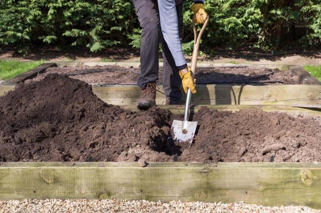 a shovel being used to dig a hole in a shallow raised bed