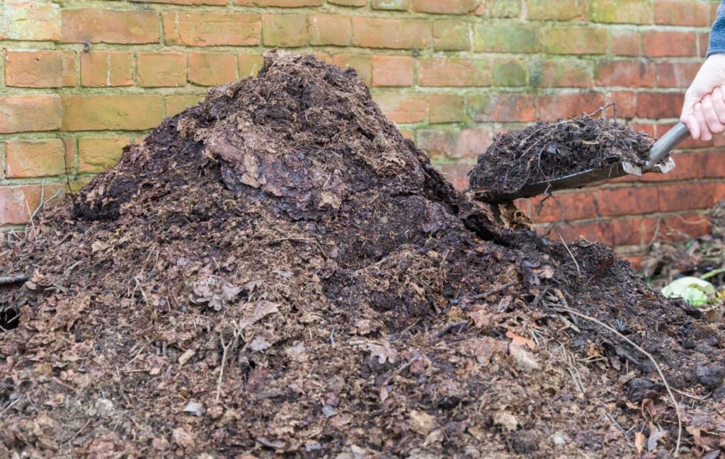a decomposing compost heap being turned over by a shovel