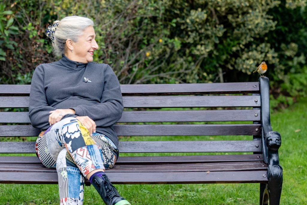 Karen Leibreich on a park bench next to a robin