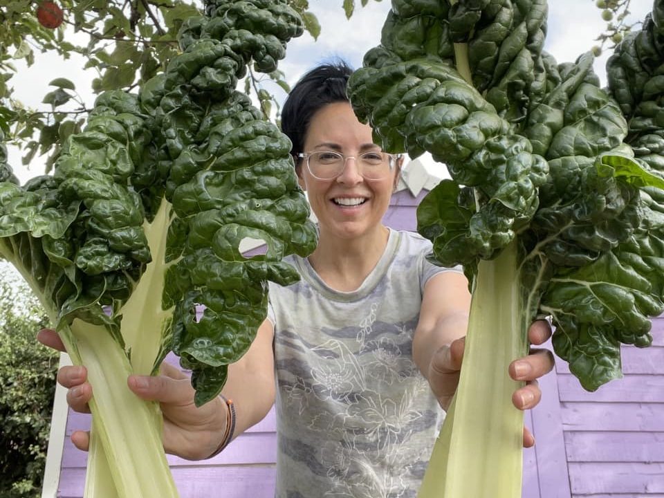 Ellen Mary holding up harvested green leafy chard