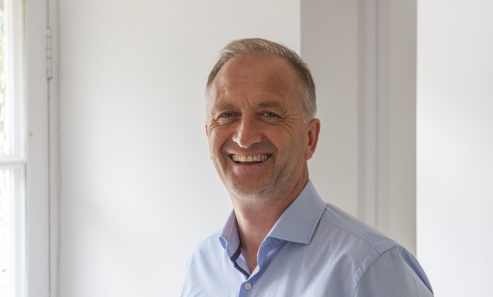 Clive Nichols smiling against a white background indoors