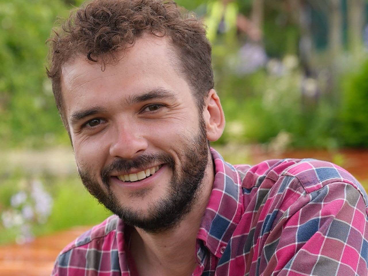 headshot of Tom Simpson smiling at the camera in a plaid shirt