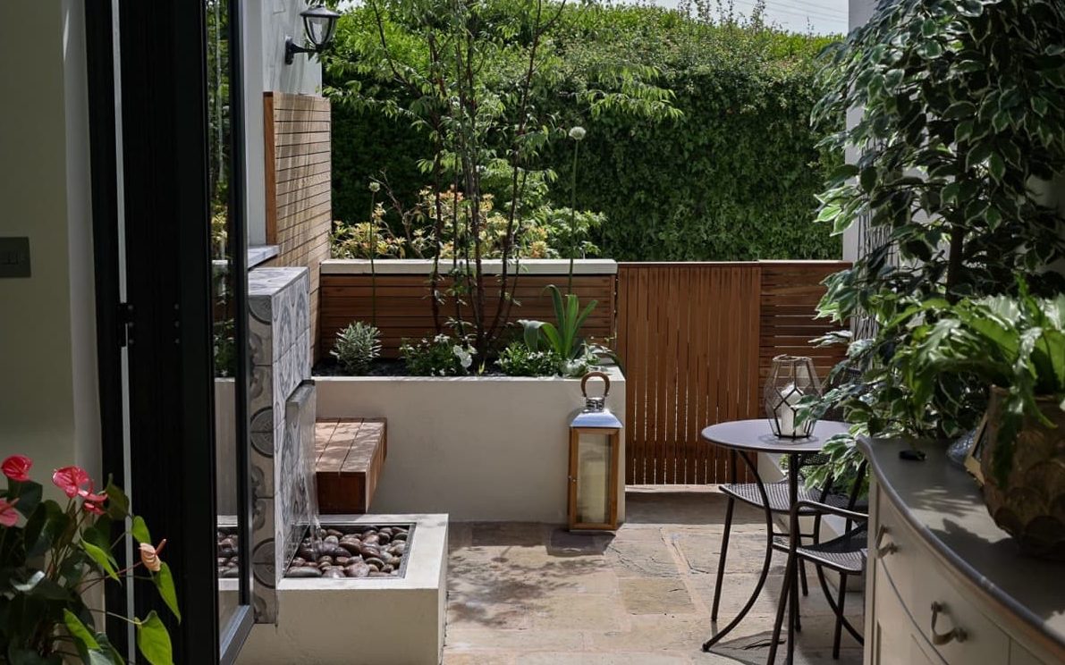 a small Mediterranean patio garden with raised planting and timber gate designed by Lisa