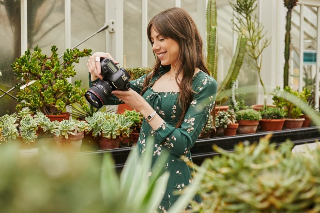 Marina Walker holding up her camera in a potted plant nursery to check the images she has just taken