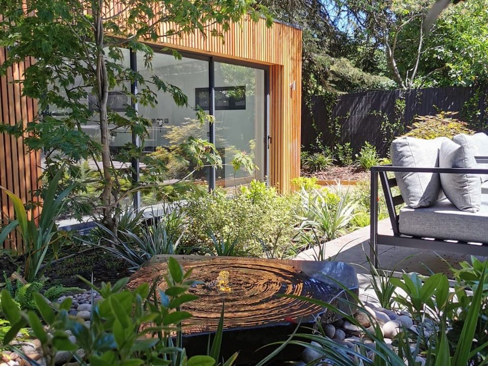 glass windows on a home extension overlooking a planting area with an outdoor sofa designed by Georgia Lindsay