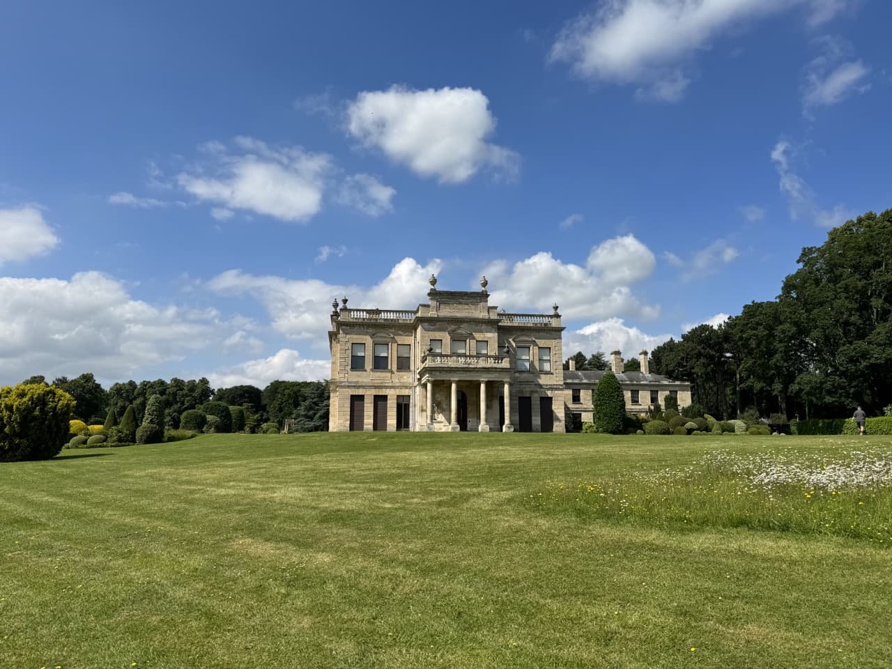 Brodsworth Hall with a blue sky and a green lawn surrounding it