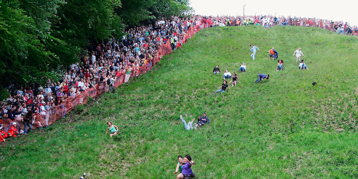 People in the UK Chase Cheese Wheels at the Cooper's Hill Cheese Roll