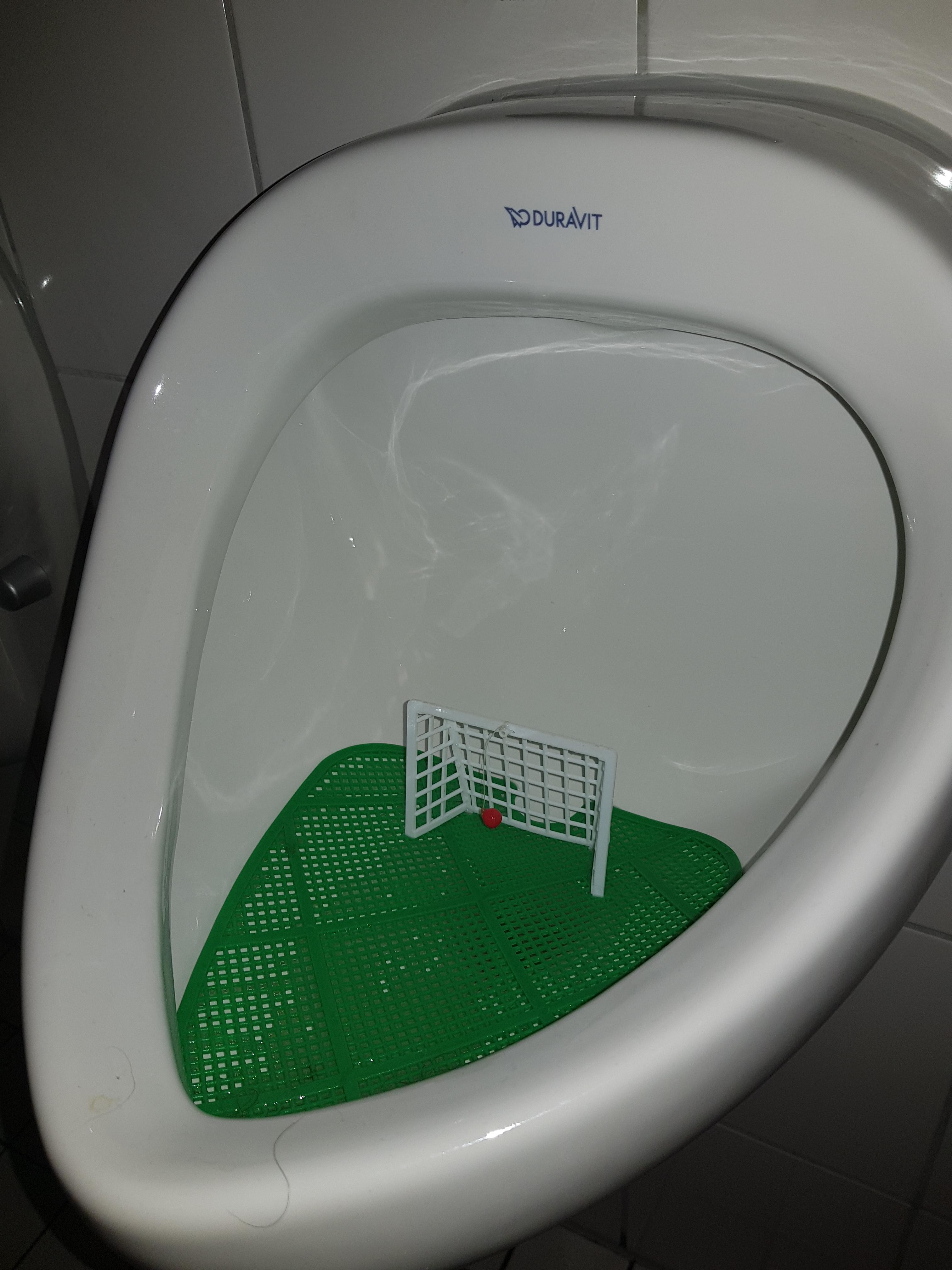 this urinal in a german bar with a soccer goal and movable ball inside