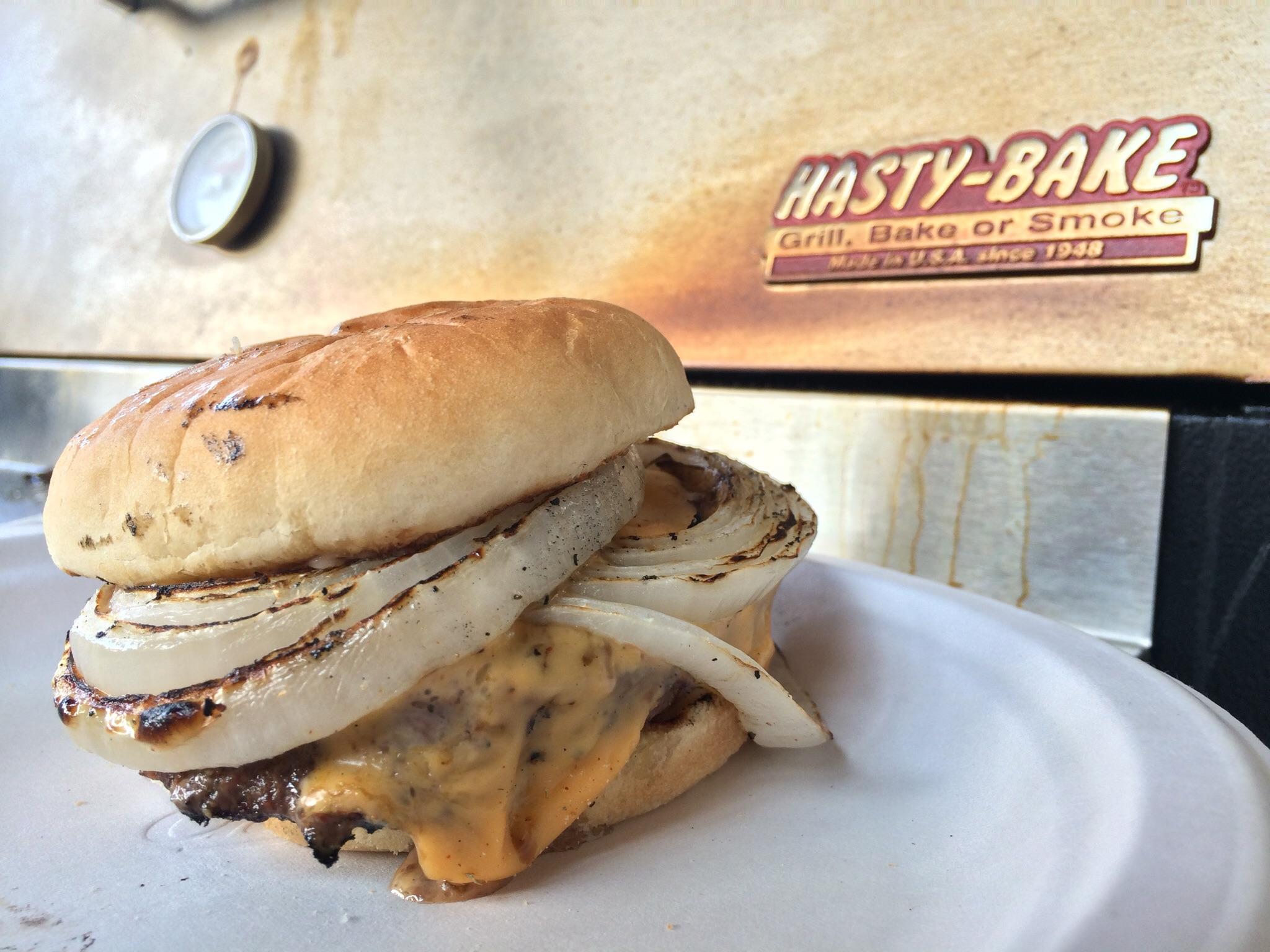 A simple charcoal grilled burger, with whole grilled onions on an