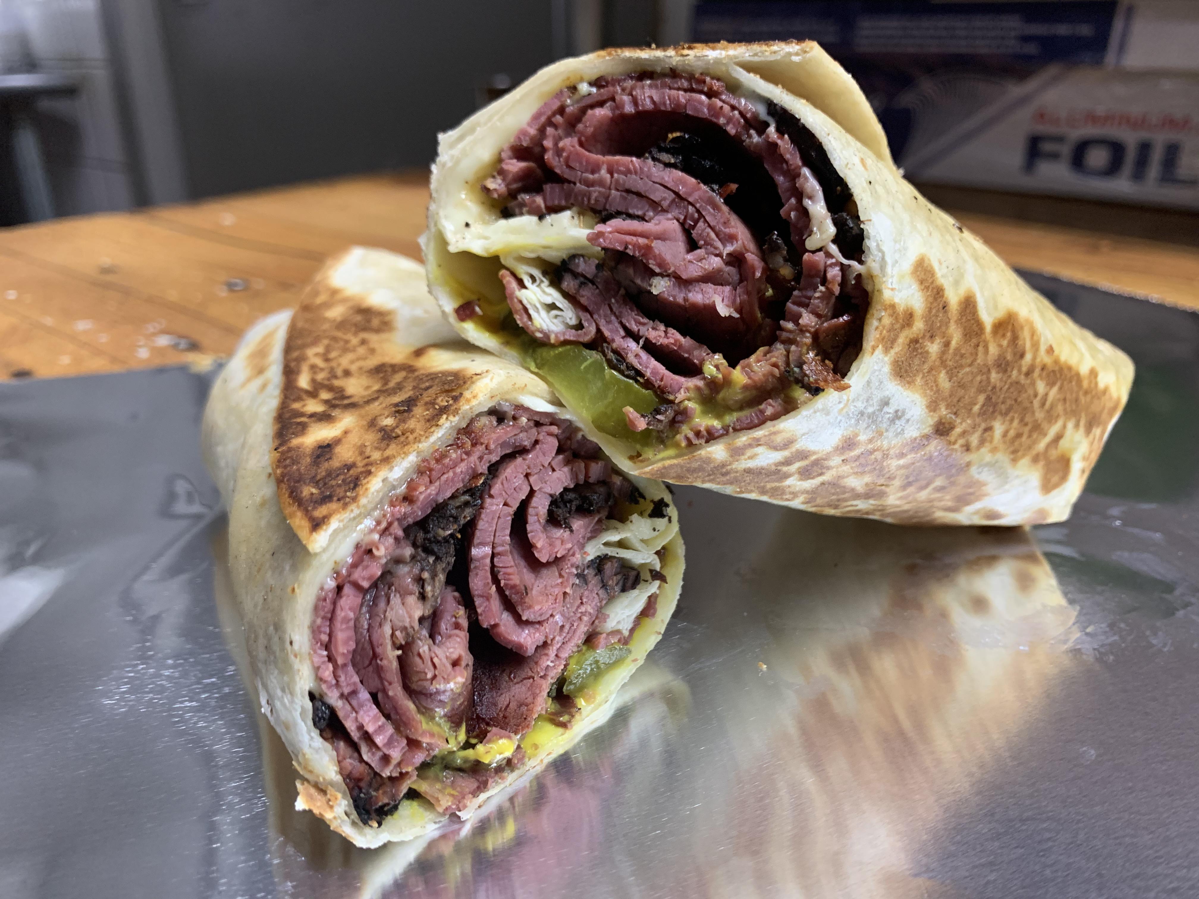 A simple pastrami wrap, toasted with Swiss, pickles, and yellow mustard