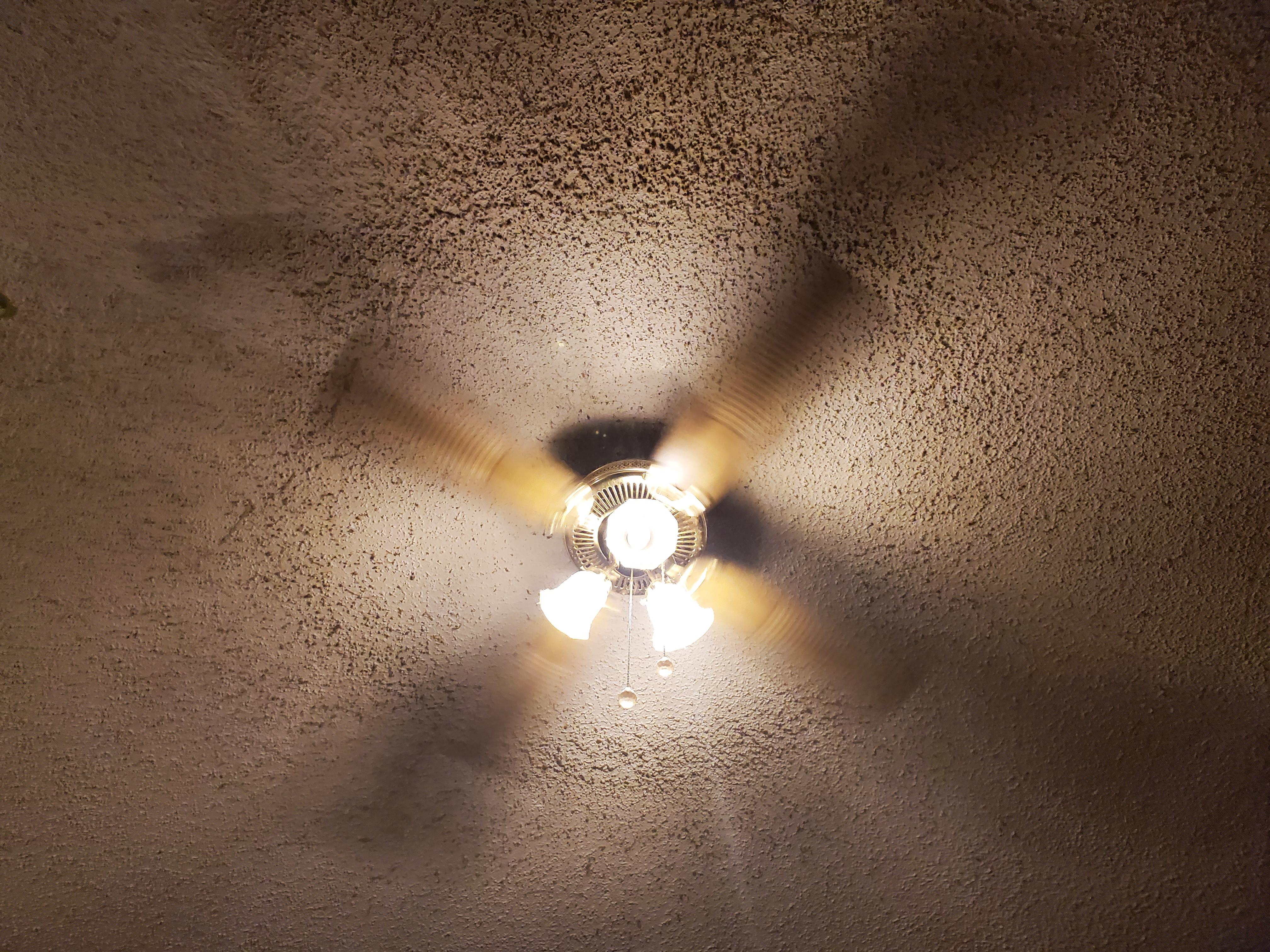 Ceiling fan with a circle of dust stuck to the popcorn ceiling. r