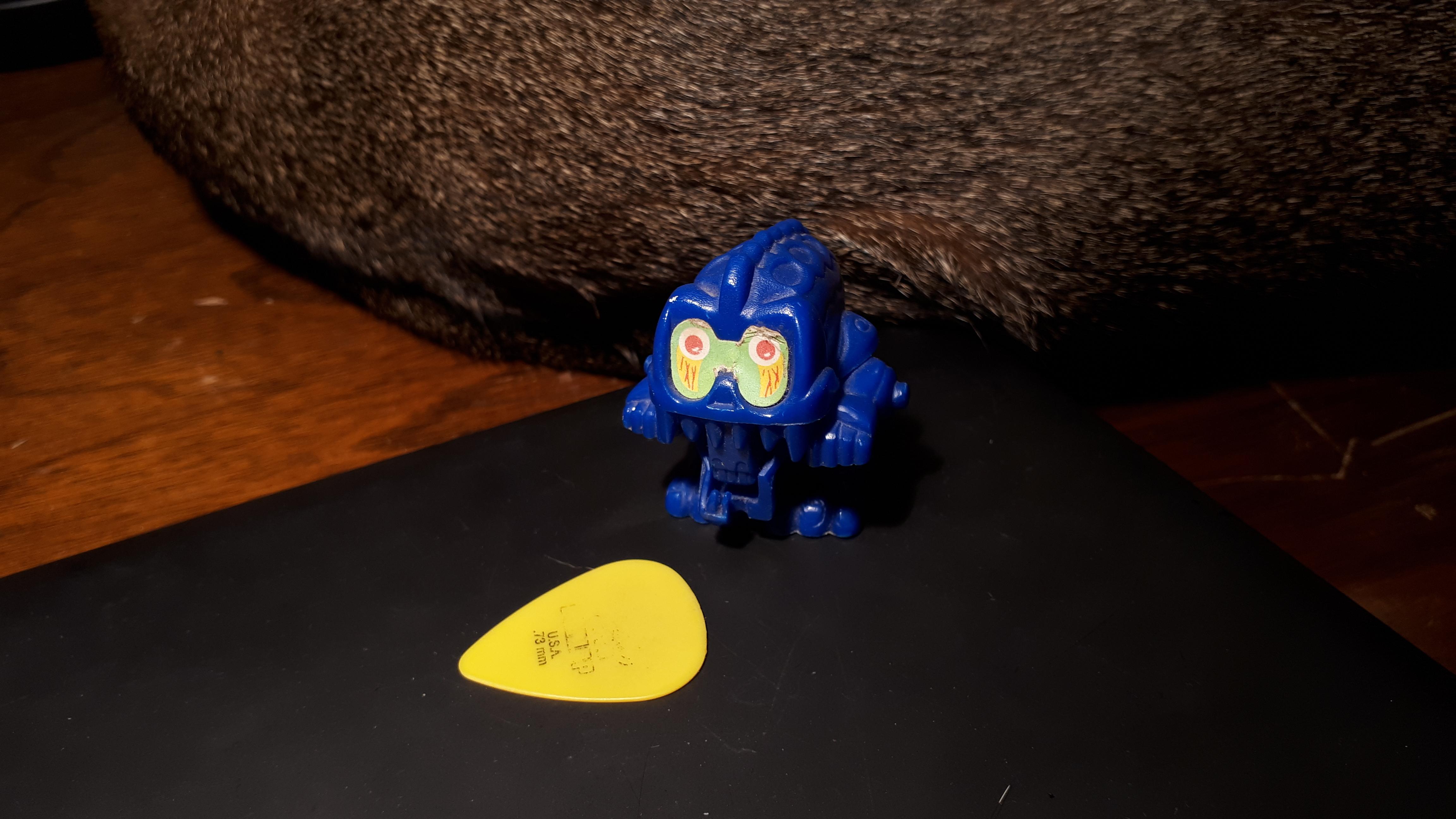 Blue alien toy? Guitar pick for scale. Found on the ground