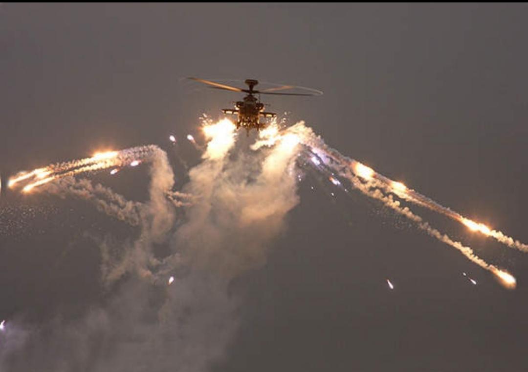 An Apache AH Mk1 helicopter launches chaff and flare countermeasures
