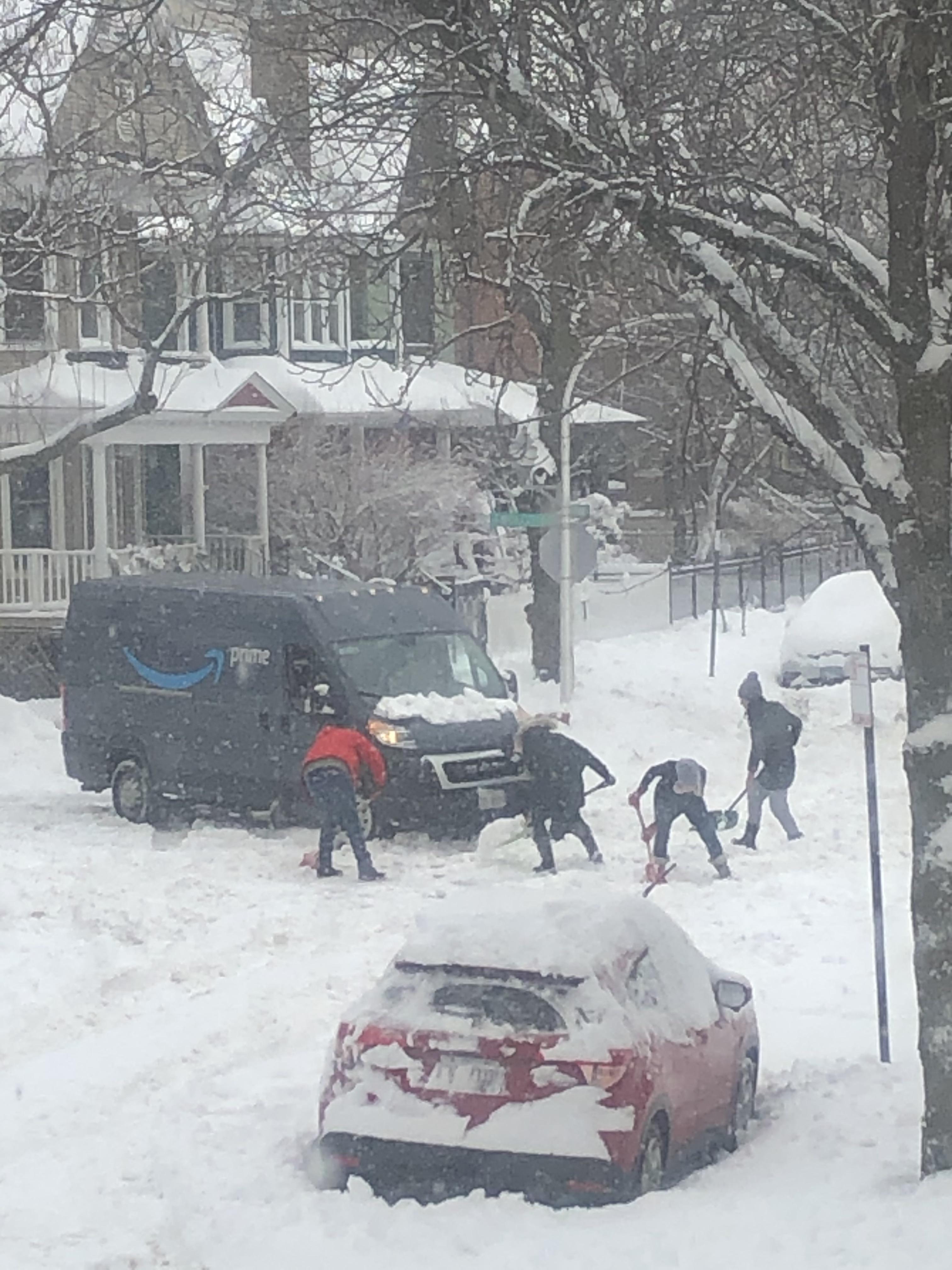 Neighbors helping dig out an Amazon truck that’s stuck in the snow r