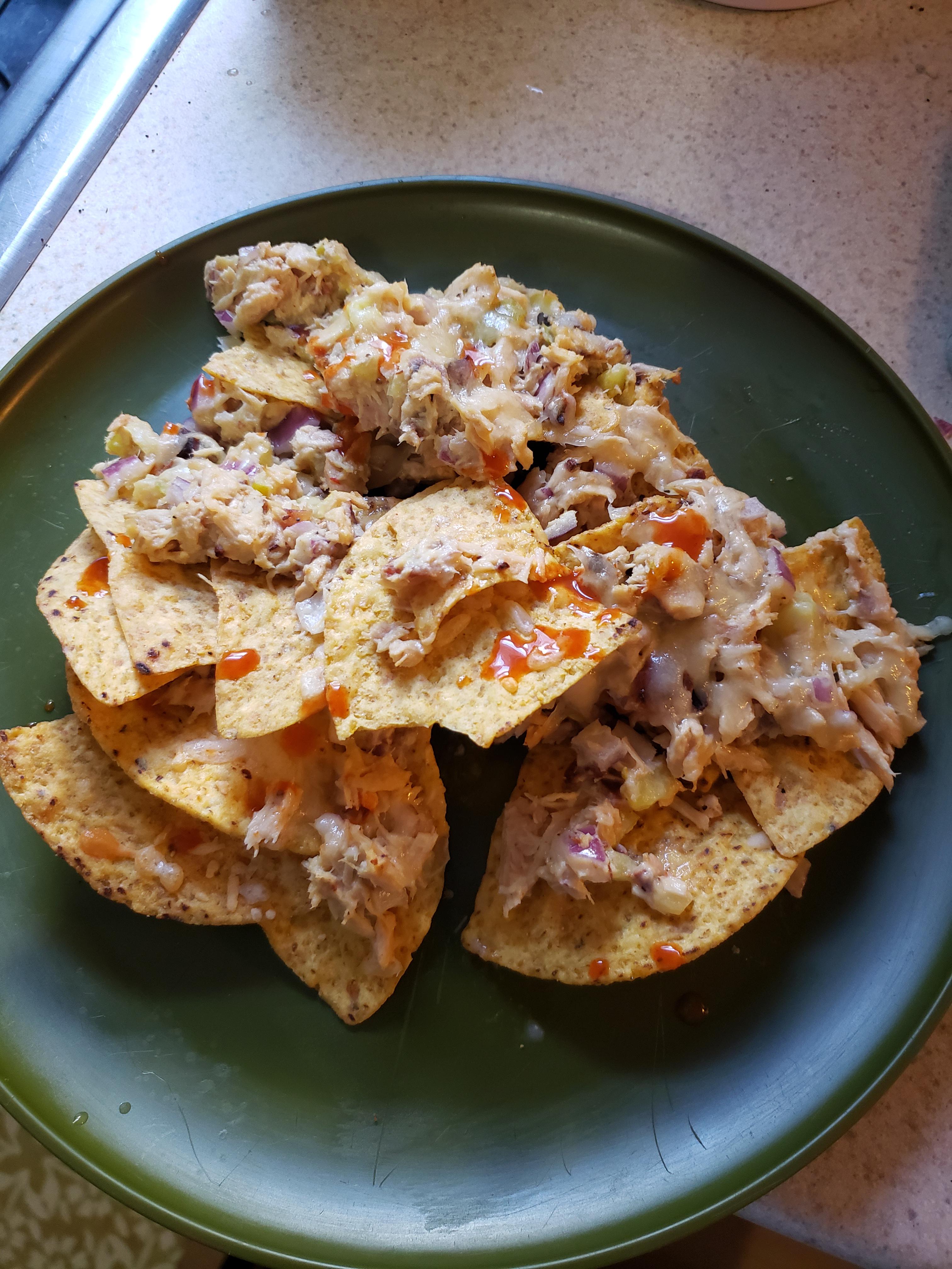 Tuna fish nachos with cheddar cheese, bacon, pickles, red onion, hummus
