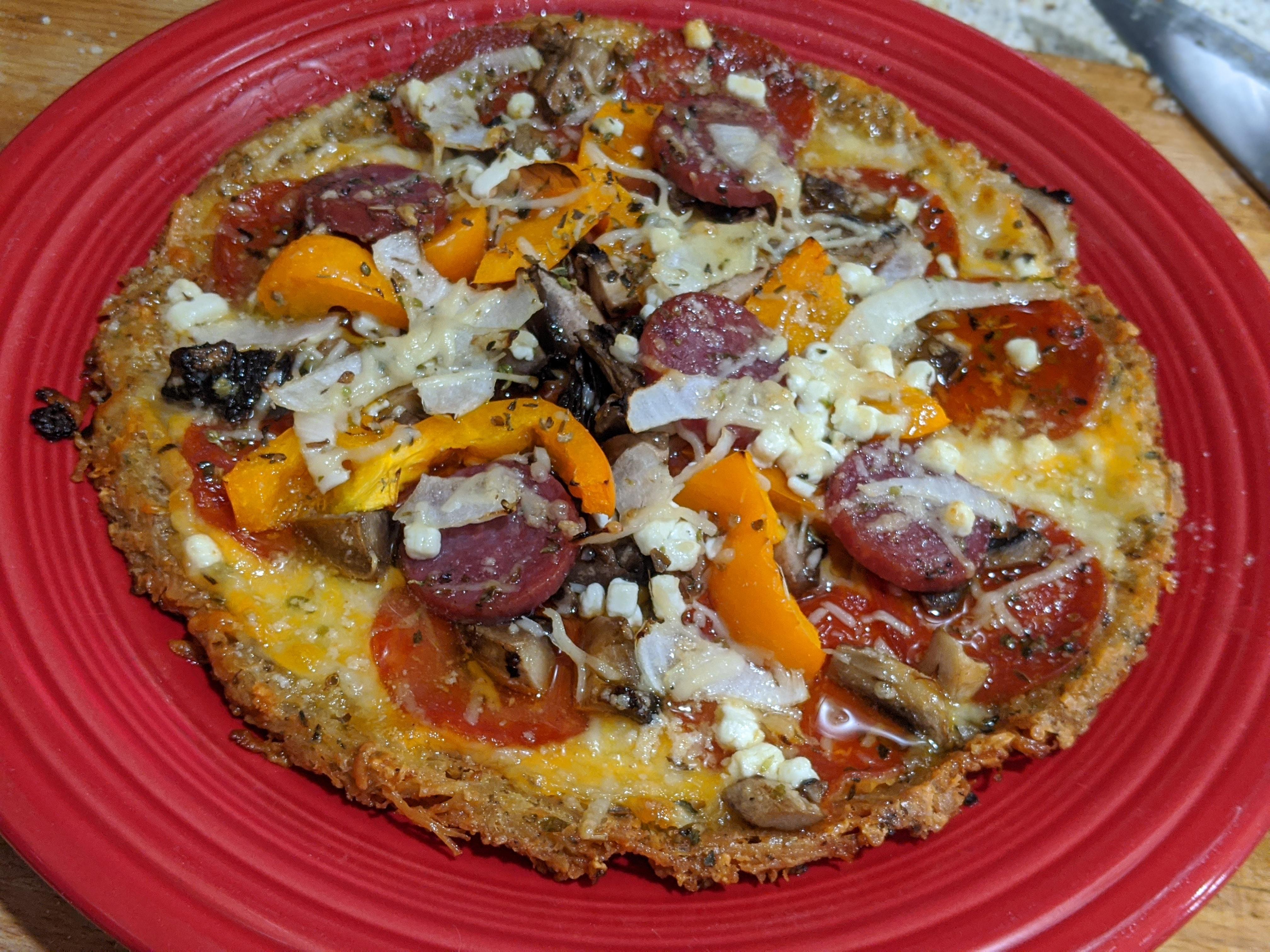Keto (Chicken crust) pizza with pepperoni, salami, orange pepper, onion and serveral cheeses