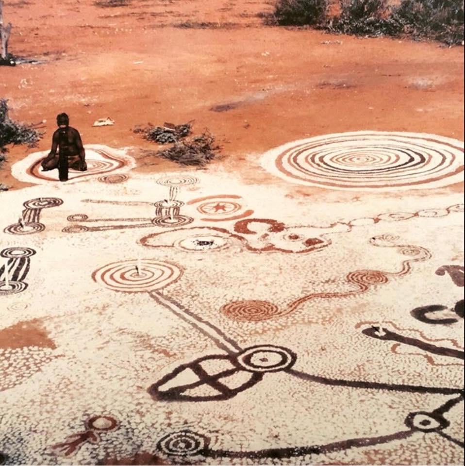 An Aboriginal man sits with his sand painting, Western Australia, early