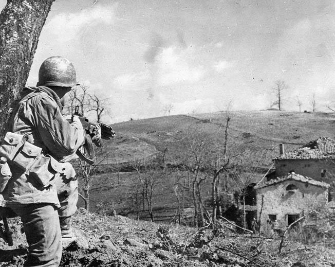 An American infantryman approaching an Italian house with caution and
