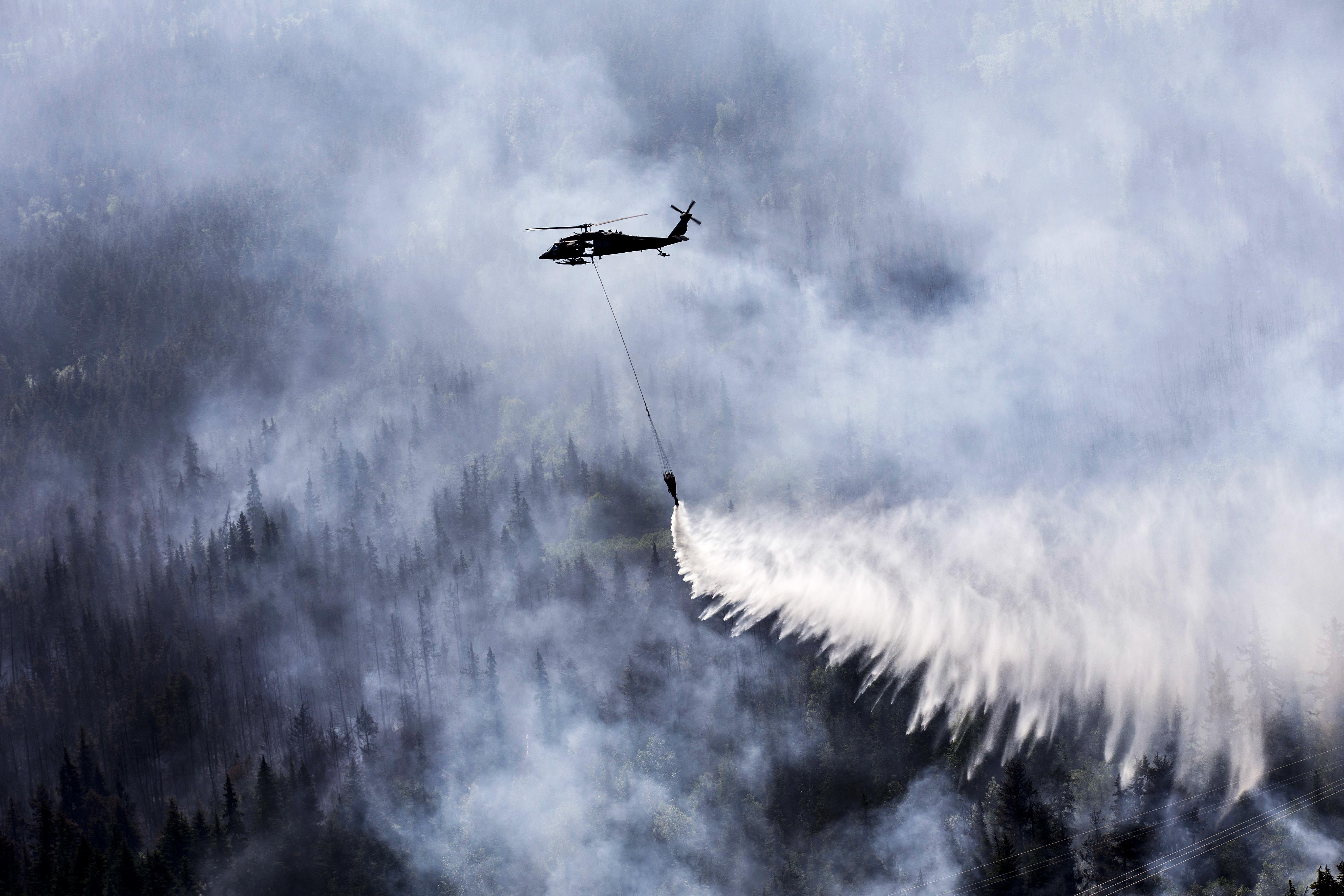 An Alaska Army National Guard UH60 Black Hawk helicopter drops gallons