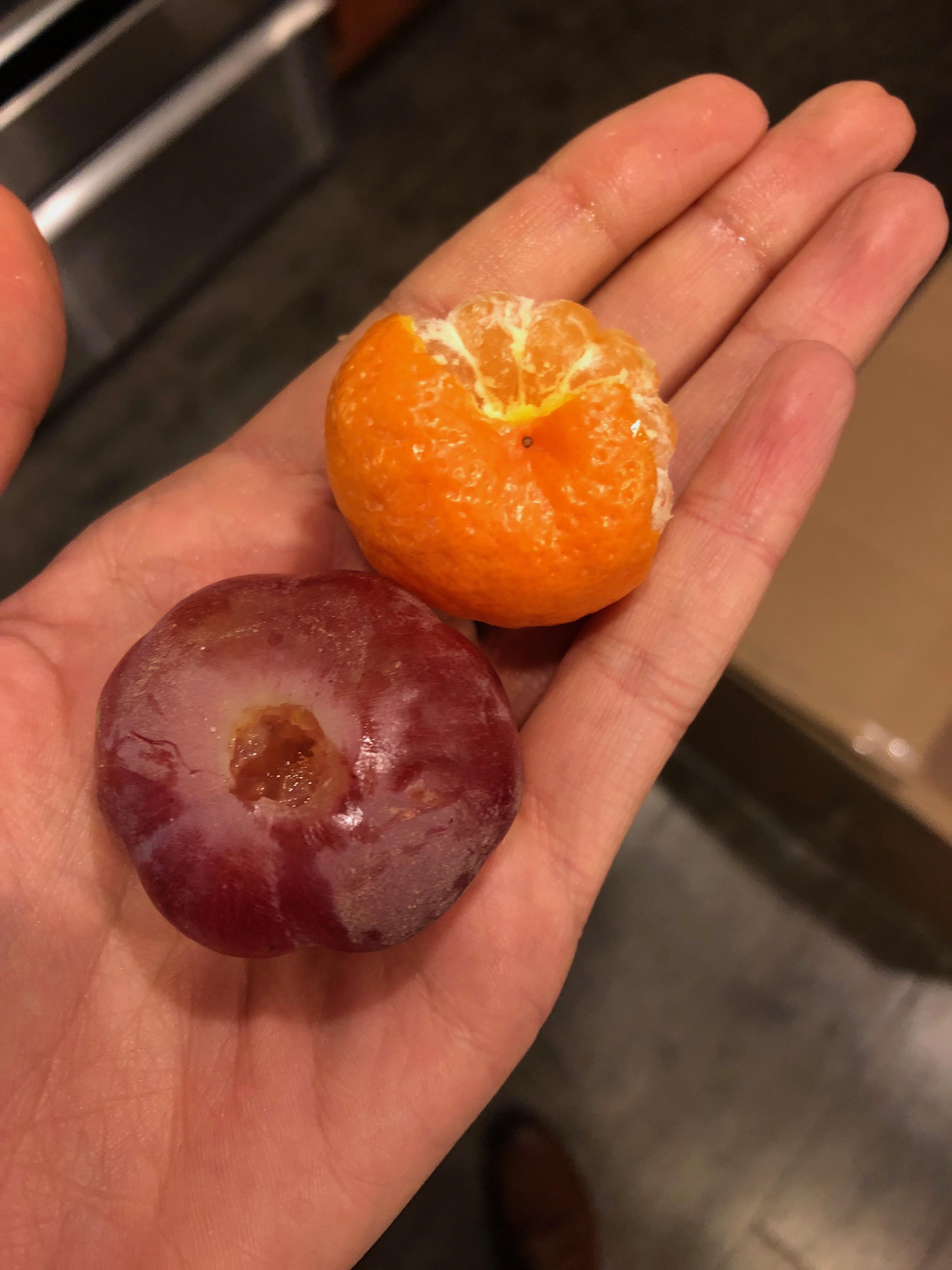 A really big grape next to a really small mandarin. r/mildlyinteresting