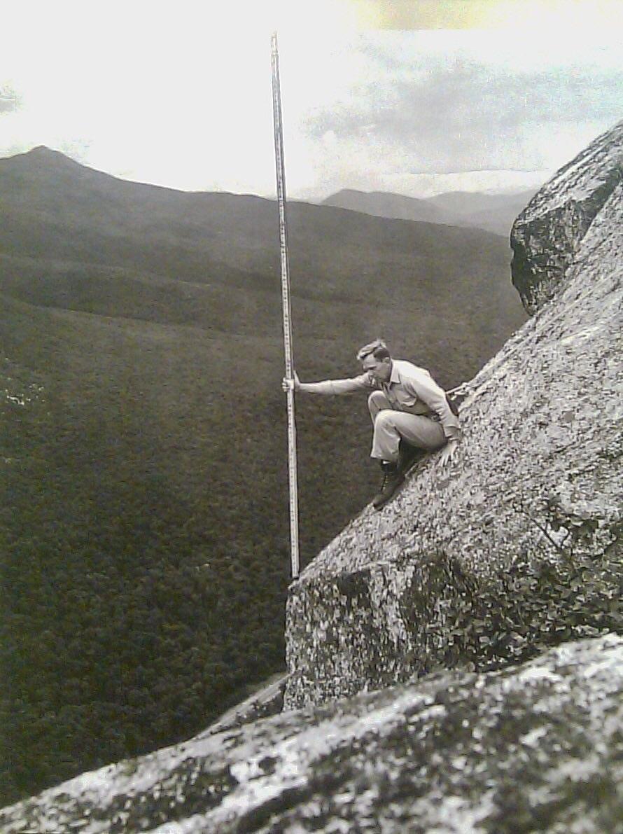 Stanton Young holds a survey rod while perched atop the Old Man of the