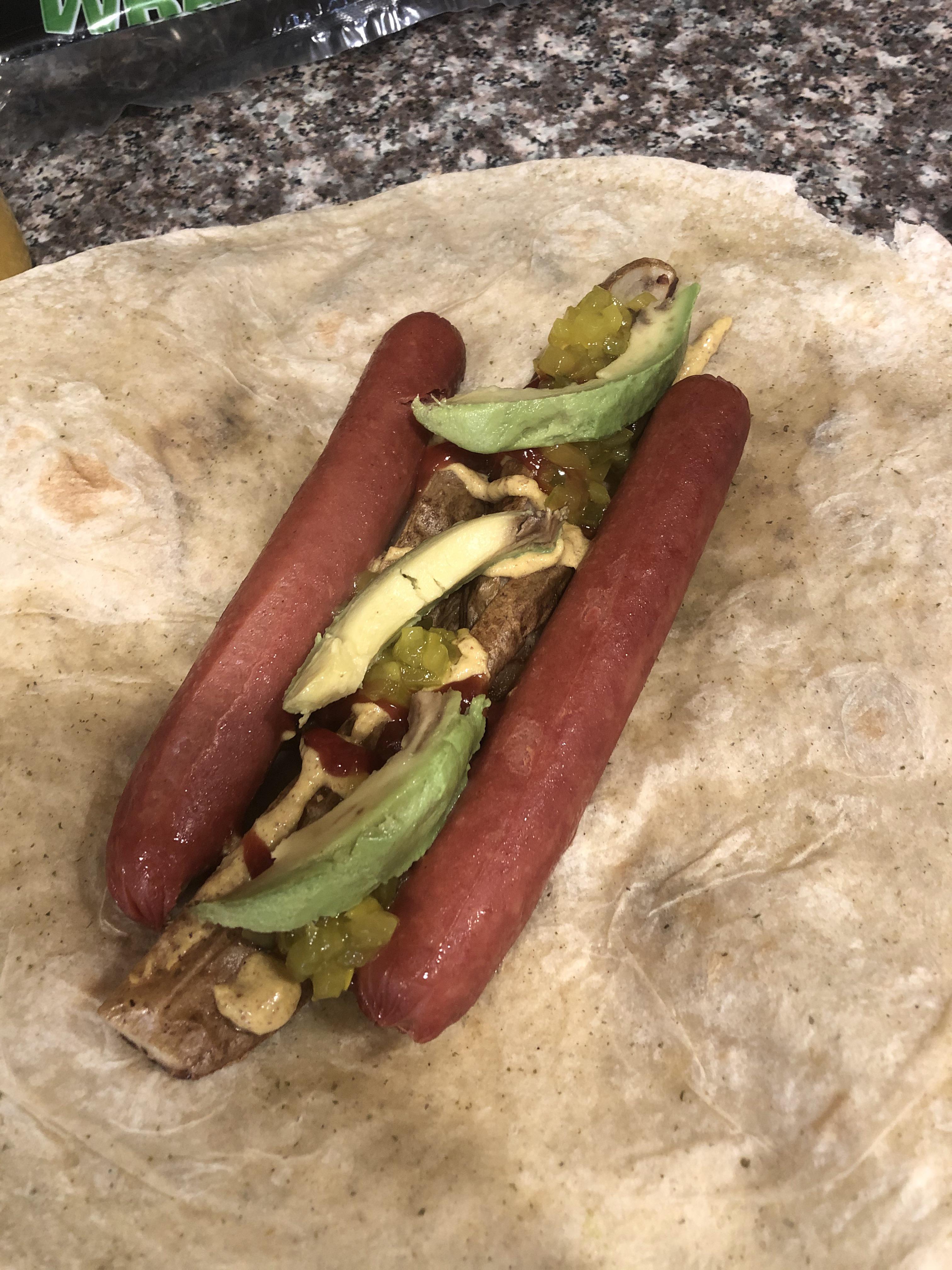 Microwaved hot dogs with potato wedges and avocado in a garlic pesto