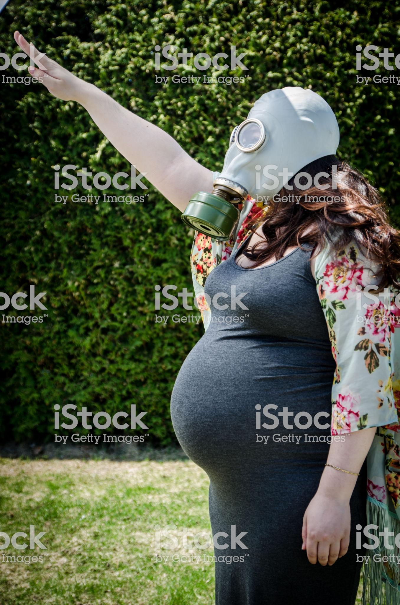 Pregnant young woman wearing a mask raising her arm to greet r